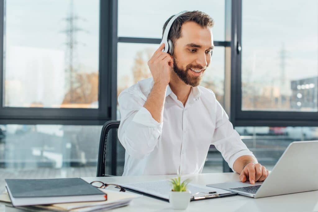 professional cheerful translator working online with headphones and laptop in office